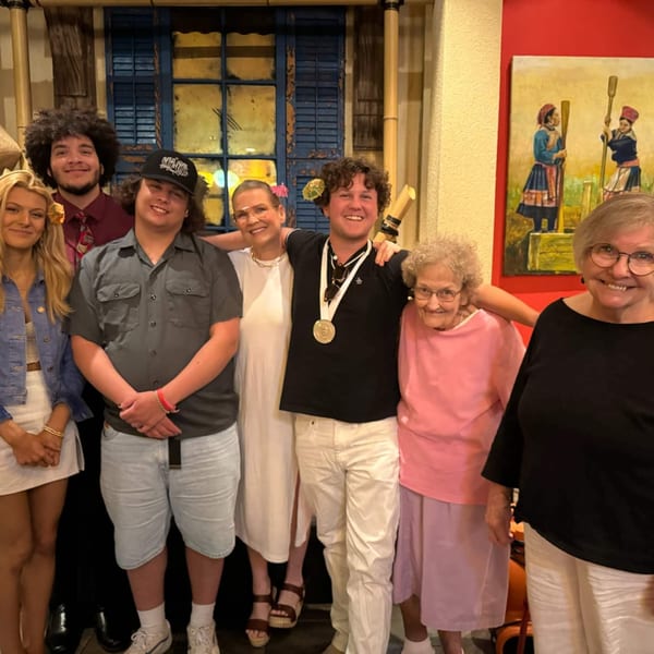 Eight smiling people of various ages posing together inside Vietnam Philadelphia restaurant.