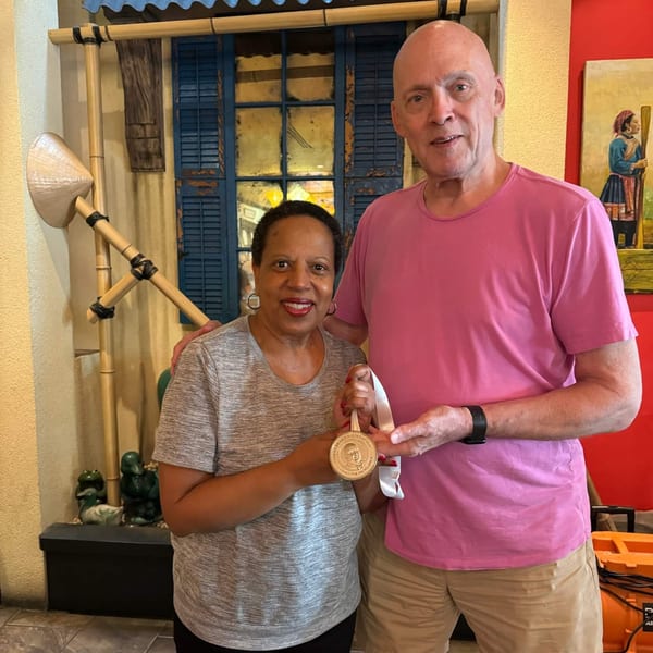 Two people, a woman and a man, holding a James Beard Foundation medal in a Vietnamese restaurant.