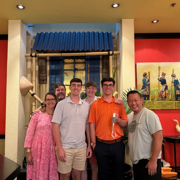 Six people, including the owner, smiling in the Vietnam Philadelphia restaurant with Vietnamese decor.