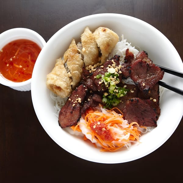 Bun Cha Gio Thit Nuong, a Vietnamese noodle dish with grilled pork, crispy spring rolls, and pickled vegetables.