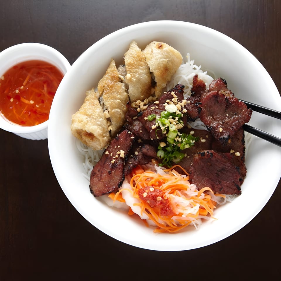 Bun Cha Gio Thit Nuong, a Vietnamese noodle dish with grilled pork, crispy spring rolls, and pickled vegetables.