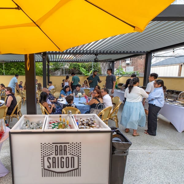 Patrons enjoying the outdoor patio at Vietnam Philadelphia, with a "Bar Saigon" cart in the foreground.
