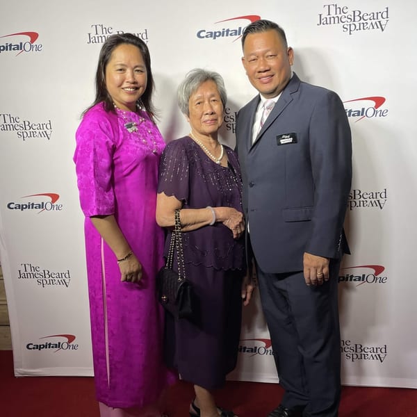 Three people, two women and one man, posing on a red carpet at The James Beard Awards.