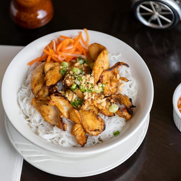 Grilled chicken, rice vermicelli, pickled carrots, and peanuts in a white bowl at Vietnam Philadelphia.